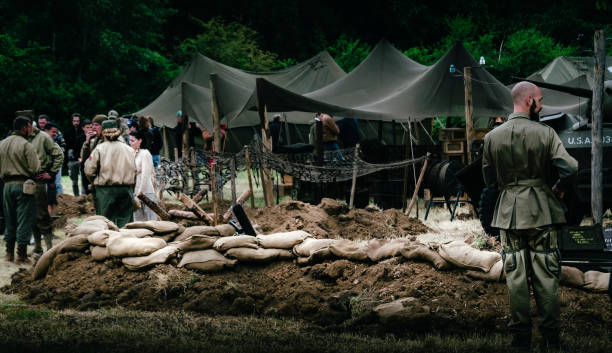 Second world war commemoration. Unidentified soldiers in military camp reconstitution next to trench with machine gun and sandbags protection.