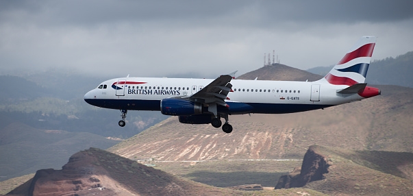 Tenerife, Spain March 31st, 2024. Airbus A320-232 British Airways Airlines flies in the blue sky with clouds. Landing at Tenerife Airport. Mountains in the background
