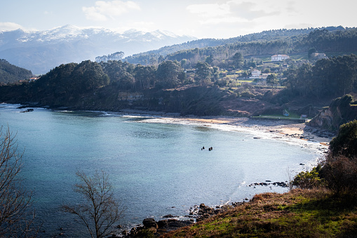 Horizontal shot captures Lastres beach, serene atmosphere, lush vegetation, gentle tones.