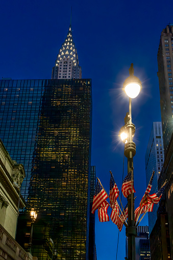 Grand Central Station in front of the Chrysler building with American flags in the foreground.