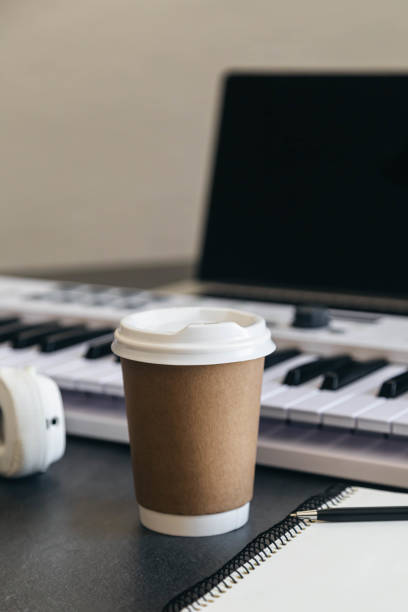 istock Musician workplace table with paper cup and white piano keyboard. 2140760173
