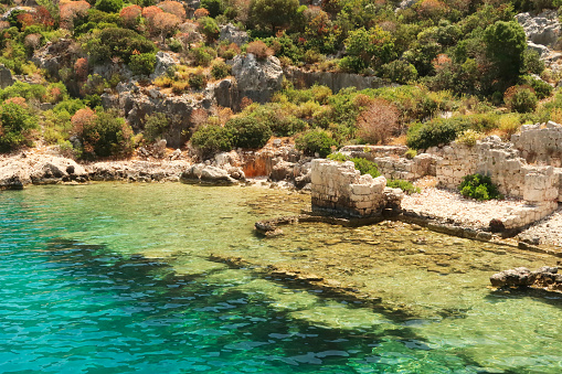 Submerged foundation next to remaining walls and structures onshore at the ancient sunken city of Kekova, Kekova Island, Demre, Turkey 2022