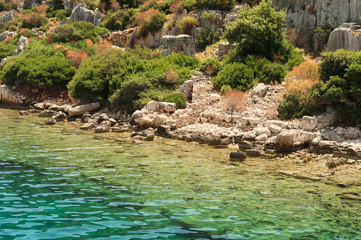 Submerged foundation next to remaining walls, structures and a doorway onshore at the ancient sunken city of Kekova, Kekova Island, Demre, Turkey 2022
