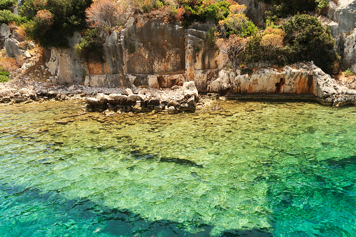 Submerged foundation in the foreground and structures and walls onshore in the background at the ancient sunken city of Kekova, Kekova Island, Demre, Turkey 2022