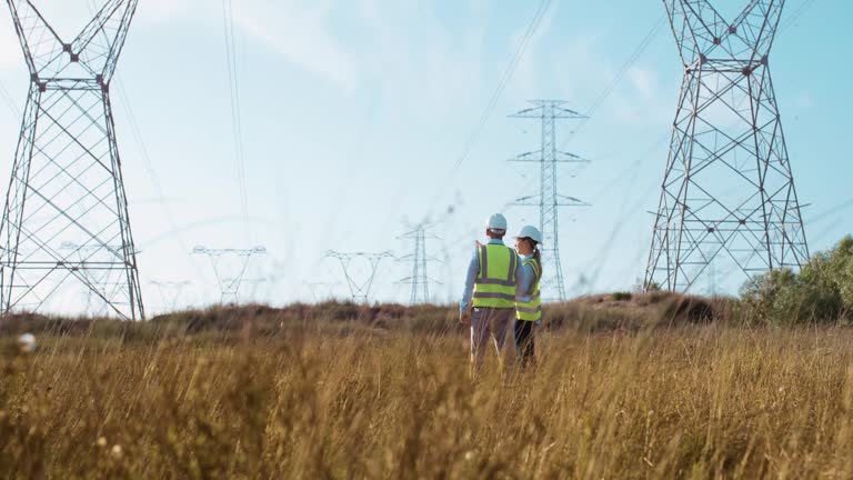 Electricians, talking and power tower for electrical distribution grid, engineer industry work. Energy production, transmission or technology ideas, maintenance for sustainable low carbon structure