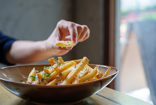 Cropped shot of a young woman delighting in a freshly served Fries with parmesan cheese and truffled mayonnaise sauce for lunch at a restaurant.