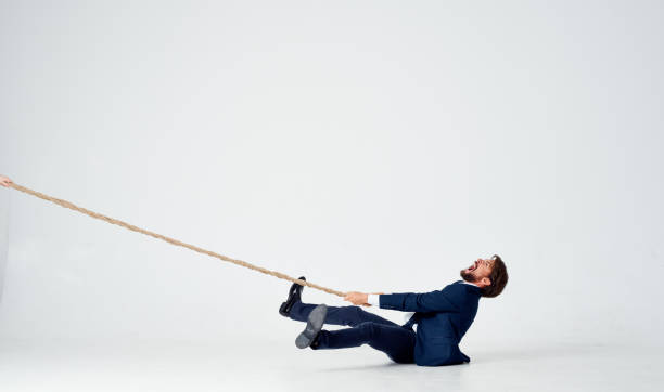 istock a business man lies on the floor and pulls a rope on a light background indoors 2140832239