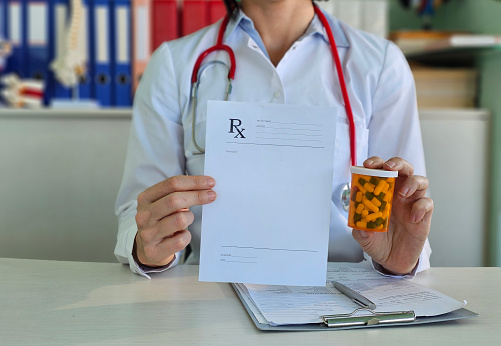 Doctor hand holding medical prescription to patient and pills in blister