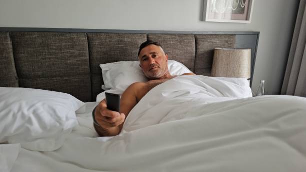 istock Man Laying in Bed Holding Remote Control 2140836974