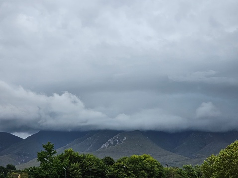 A view of a mountain range under a cloudy sky. The clouds cover the mountain peaks