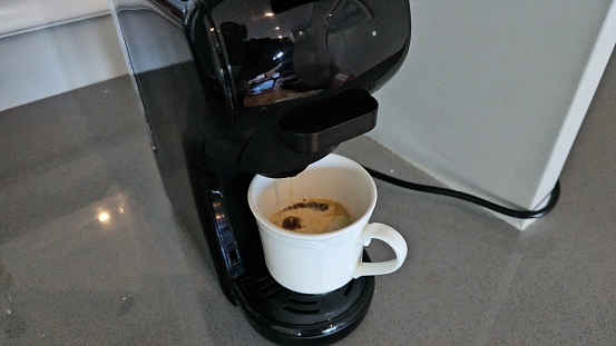 A cup filled with coffee is placed on top of a coffee maker