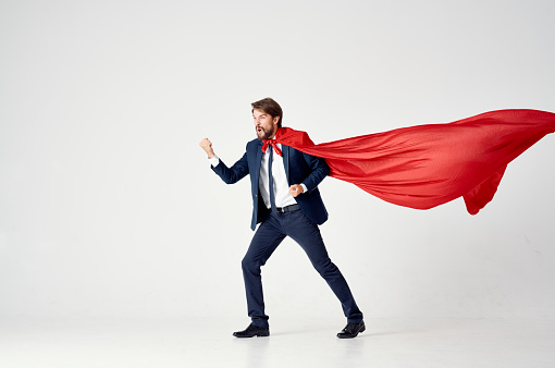 business man in a red cloak on a light background looks to the side success superhero suit. High quality photo