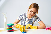 Cheerful cleaning lady wipes the table with detergents cleaning tools