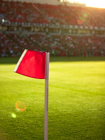 Soccer corner flag on the grass stadium field in the evening during a game