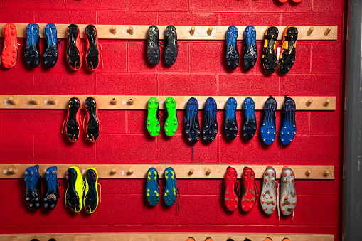 Football boots hanging in a locker room for the players in a stadium