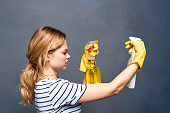 Cleaning lady in yellow rubber gloves detergents home care gray background