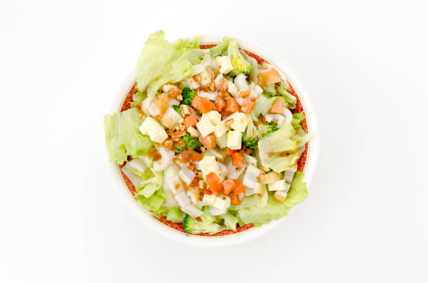colorful fresh vegetable salad with spicy sausage and chikuwa in a white bowl on white background.