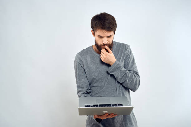 istock A man holding a laptop internet communication lifestyle technology light background studio 2140940857