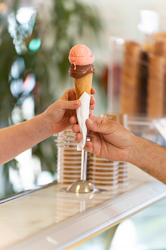 Close-up of a man is serving an ice cream cone of various flavors to a woman