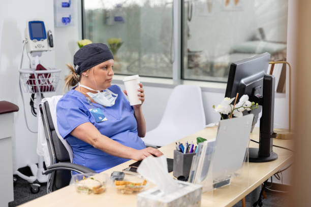 istock Expecting female surgeon works at her desk while on her lunch break 2140945686