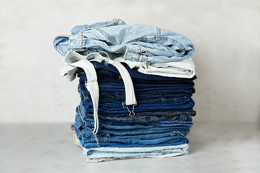 A stack of folded denim clothes on a gray background.