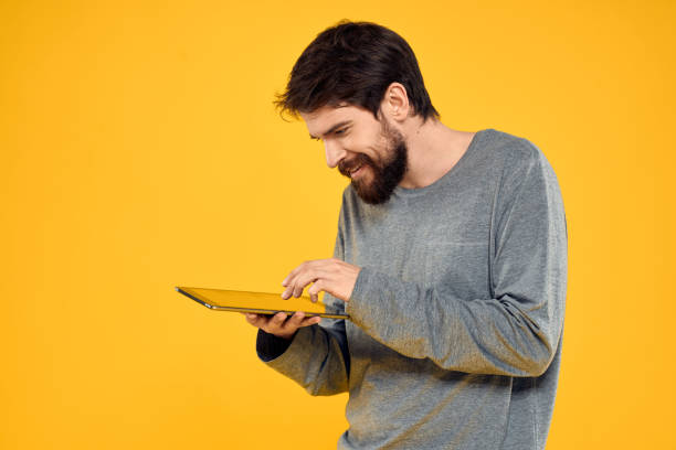 istock Emotional man with tablet in hands technology internet device lifestyle yellow background 2140956337