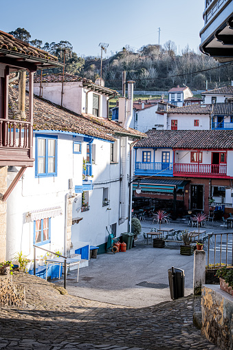 Sunny rural village square in Lastres, Asturias, with vibrant colored stone and wood houses.