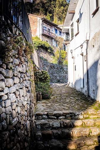 Beautiful stone-paved pedestrian street with white house and rural Lastres village in background.