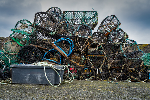 A pile of fishing nets and traps are stacked on top of each other. The scene is somewhat chaotic and disorganized, with the nets and traps of various sizes and shapes scattered around