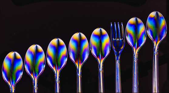 Photelasticity (optical stress or birefringence) shot of plastic cutlery (spoons and a fork)  using a polarising filter and a laptop screen - odd one out