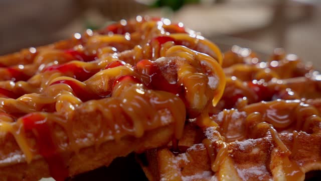 Belgian waffles decorated with caramel and raspberry sauce. Concept of delicious baking.