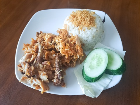Delicious Nasi Ayam Geprek Or Smashed Fried Chicken Rice With Cucumber Slices, Cabbage And Crispy Spiced Flakes. Food Menu.
