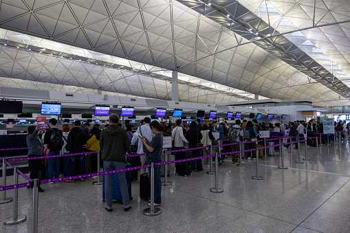 Hong Kong - March 18, 2024 : Travelers at the HK Express check-in counters at departure hall of the Hong Kong International Airport in Hong Kong.