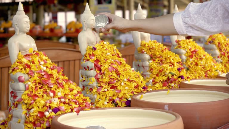 Beautiful young woman's hands pour water on a Buddha statue during Songkran, Thai New Year.