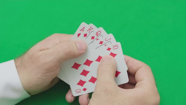 man moves playing cards with red combination of diamonds in poker flush royal, slow motion, selective focus