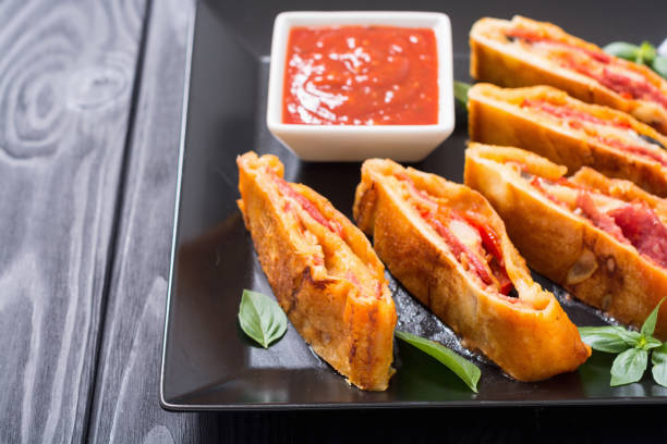 Italian food Pizza roll stromboli with cheese , salami , olives and tomatoes