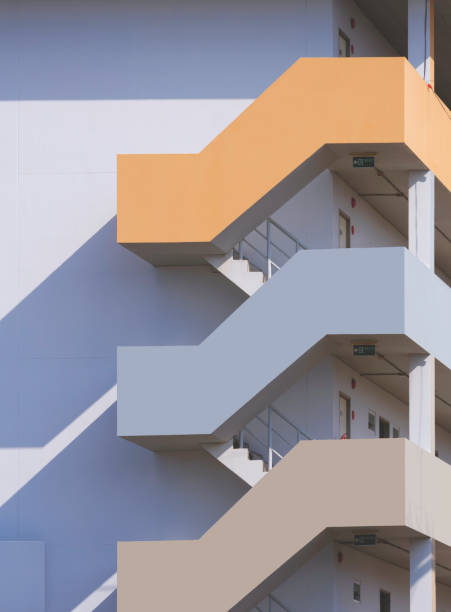 multicolored fire escape outside of apartment building in vertical frame with sunlight and shadow on surface, exterior architecture background in minimal style