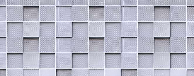 Geometric square pattern background of expanded aluminum grating wall decoration outside of modern building in panoramic view