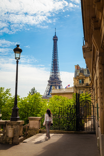 The Tour Eiffel seen from a street of Paris and a girl walking by