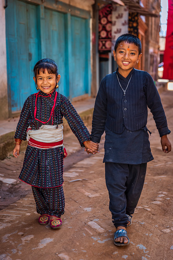 Nepali children wearing traditional Newari clothes going to the festival in an ancient town of Bhaktapur. Bhaktapur is an ancient town in the Kathmandu Valley and is listed as a World Heritage Site by UNESCO for its rich culture, temples, and wood, metal and stone artwork.
