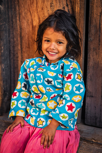 Portrait of Nepali little girl posing in an ancient town of Bhaktapur. Bhaktapur is an ancient town in the Kathmandu Valley and is listed as a World Heritage Site by UNESCO for its rich culture, temples, and wood, metal and stone artwork.