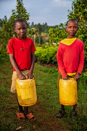 African children carrying water to their village, Kenya, Africa. African children and women often walk long distances to bring back containers of water.