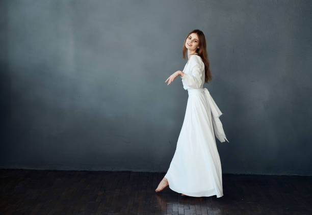 istock Charming lady in a white dress on a gray background dance gesticulating with her hands Copy Space model 2141178319