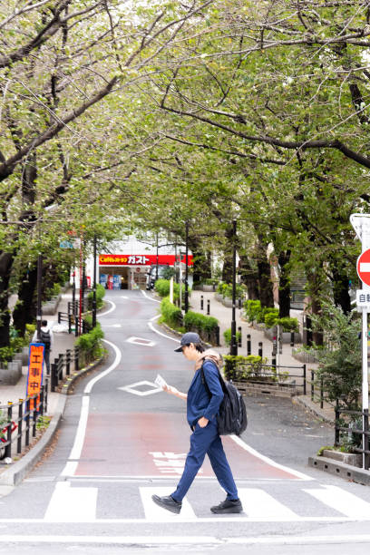 Tokyo, Japan - October 7, 2023: A single man in a suit crossing the road at an intersection in the Aobadai, Meguro City district of Tokyo.