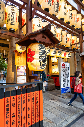 Kyoto, Japan - October 9, 2023: Rows of multiple yellow Japanese paper lanterns glowing in the famous Nishiki Market food street in Kyoto, Japan.