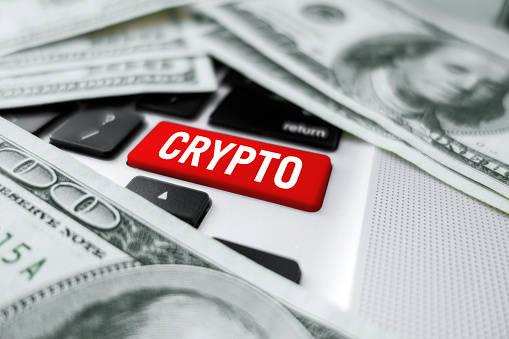 ‘Cryptocurrency’ enter key on computer keyboard with 100 dollar bills