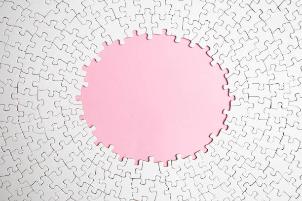 istock Plain white jigsaw puzzle  on pink  color background, oval shaped frame, abstract backdrop 2141233860