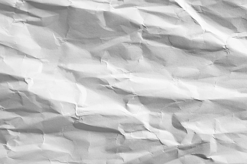 White paper crumpled with shadowed wrinkles, soft focus close up, abstract texture