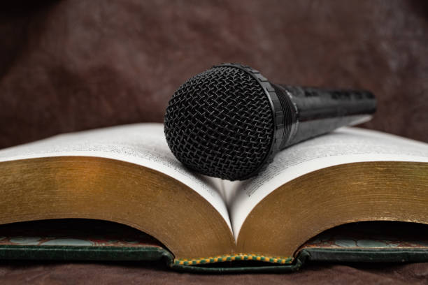Microphone on a opened book with golden pages, audio book concept, soft focus close up