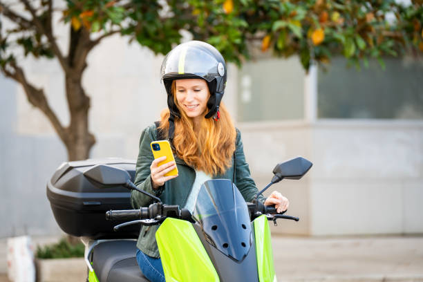 istock Red-haired woman on her motorcycle using smart phone 2141265362